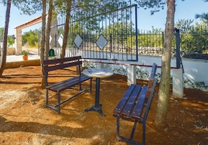 A park with a wooden bench, a small round table, and a metal fence. - House Kristiana (Supetar)