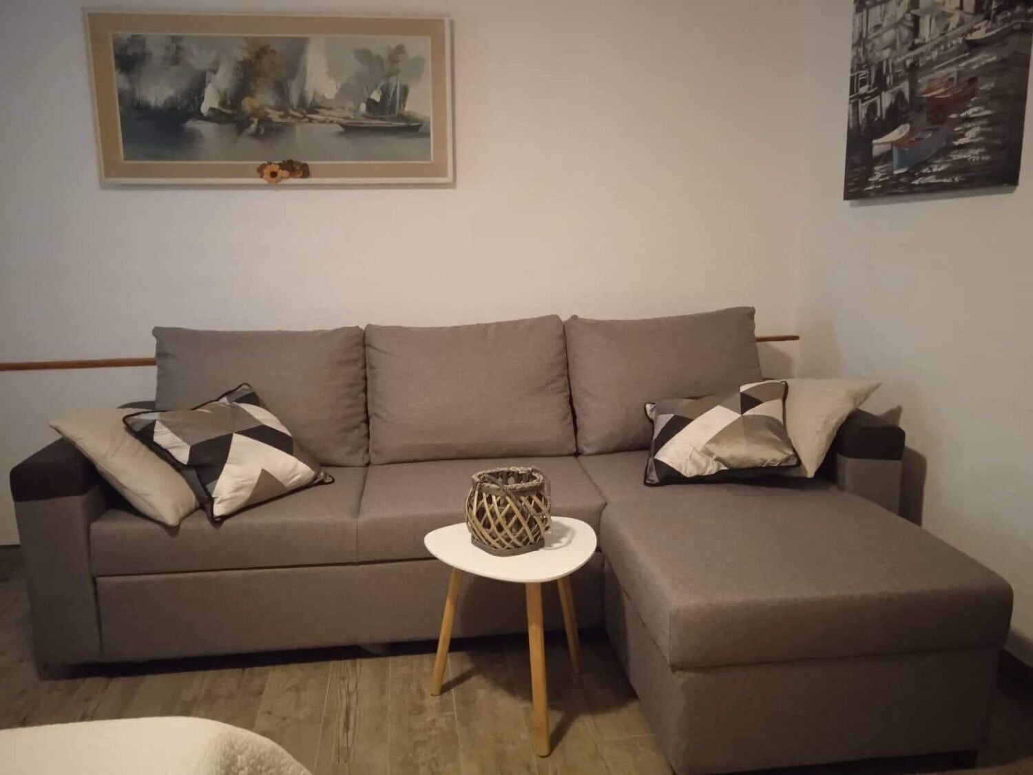 A living room with a sofa, a small side table, and two cushions.