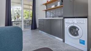 Una cocina moderna con armarios grises, lavadora integrada y comedor con mesa y sillas.