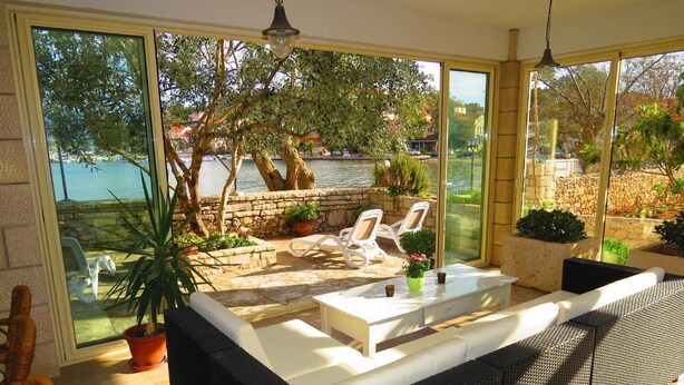 A sunlit patio with a white sofa, two white chairs, and a small table with a potted plant. - House Villa Barakokula (Lumbarda)