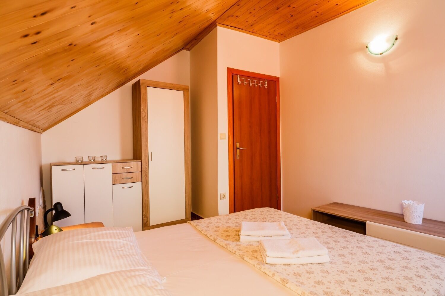 Une chambre à coucher comprenant un lit, une armoire, une table de chevet et un luminaire au plafond.