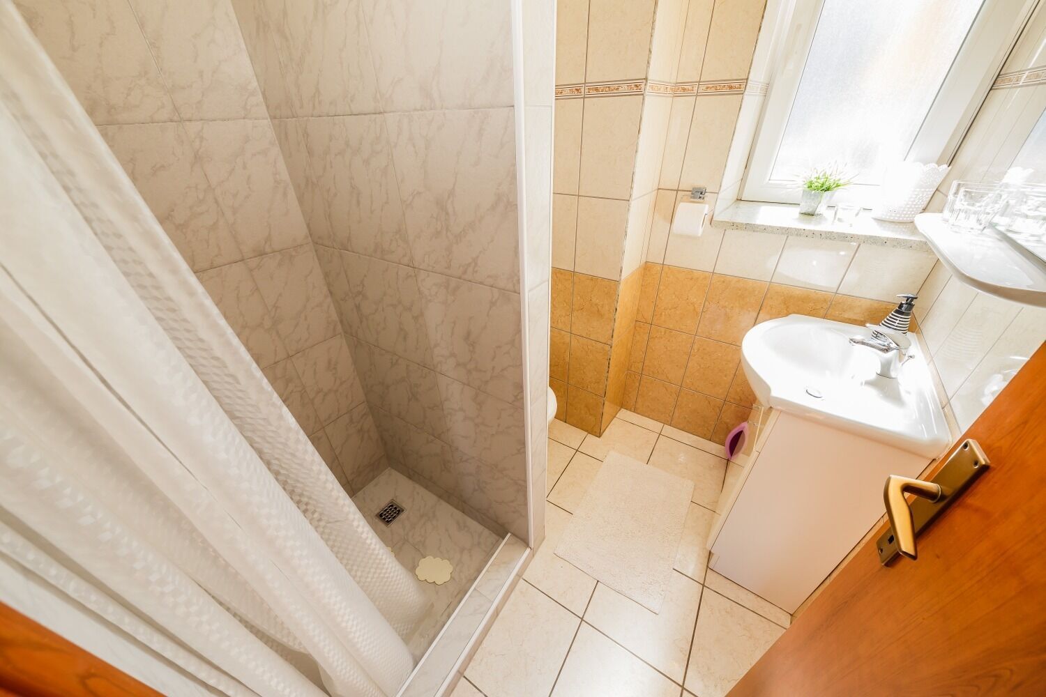 A bathroom with a shower, sink, and mirror.