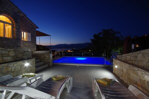 Un edificio in pietra con piscina e area salotto all'aperto.