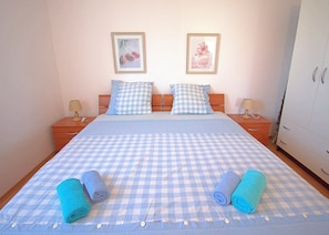 A bedroom with a checkered bedspread, two pillows, two bedside tables with lamps, and a wardrobe. - Apartment Zita (Rogoznica)