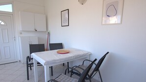 A dining area with a white table, black chairs, and a red plate on the table. - Apartment Zita (Rogoznica)