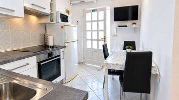 Une cuisine compacte équipée d’un four encastré, d’un four à micro-ondes et d’un coin repas avec une table et des chaises.