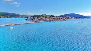 A coastal town with a pier extending into the sea, surrounded by buildings and hills. - Apartment Zita (Rogoznica)