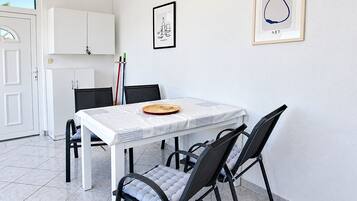 A dining area with a white table, black chairs, a white cabinet, and two framed artworks on the wall.