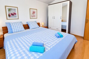 A neatly made bed with a checkered bedspread, two pillows, and two rolled towels. - Apartment Zita (Rogoznica)