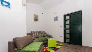 A small, modern living room with a sofa, a colorful rug, and a green door. - Apartment Tamara (Okrug)