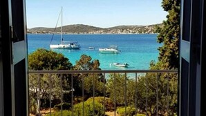Un balcone con vista sul mare, barche e una costa lontana.