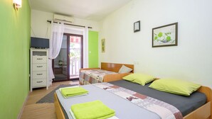 A bedroom with two beds, a wardrobe, a television, and a window with curtains. - Apartments Ani (Crikvenica)