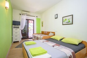 Una camera da letto con due letti, un armadio, una televisione e una finestra con tende.