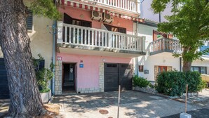 A two-story building with a balcony, a door, and a small garden area. - Apartments Ani (Crikvenica)