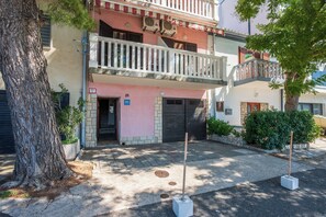 Un edificio a due piani con un balcone, una porta e un piccolo giardino.