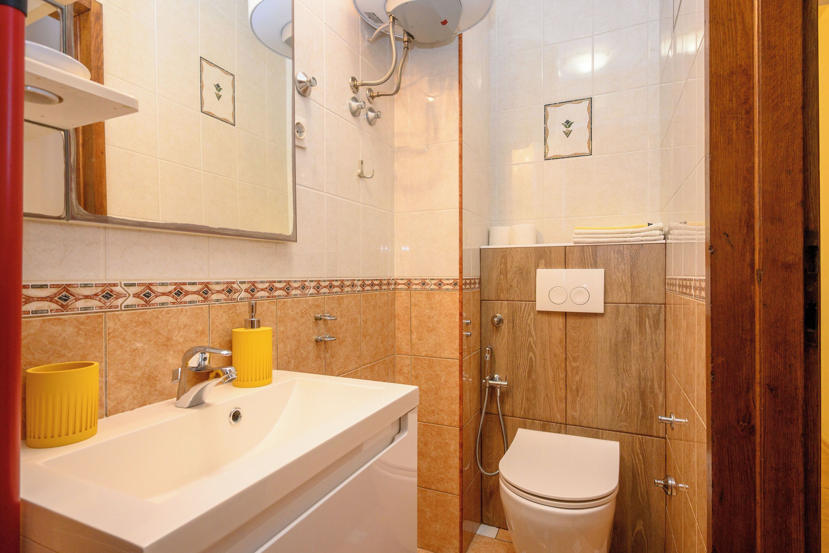 A bathroom with a sink, mirror, toilet, and shower.