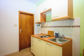 Una cucina compatta con una porta in legno, un lavello doppio e un piccolo piano di lavoro.
