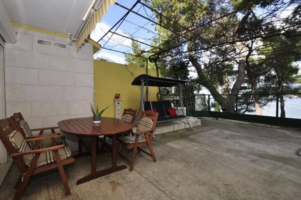 A patio with a round wooden table and chairs, a small potted plant, and a swing chair.