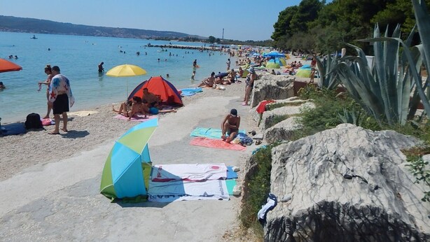 Una playa con gente tomando el sol y nadando.