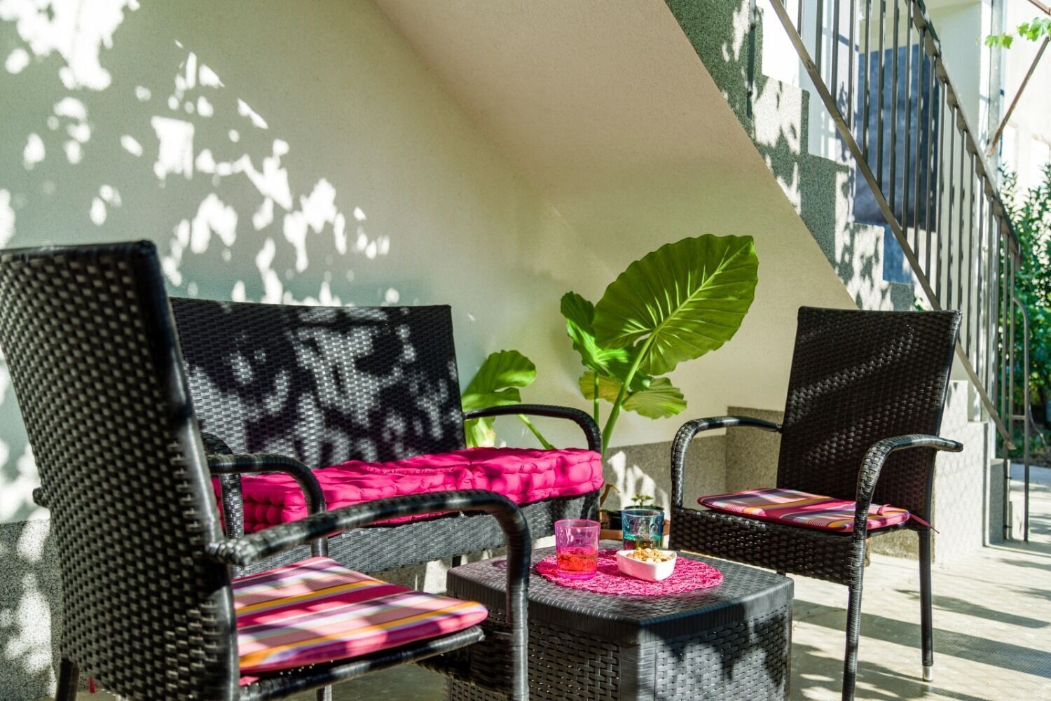 Ein Patio mit Korbstühlen und einem kleinen Tisch, einschließlich eines Blumentopfs und einer Dekoration.