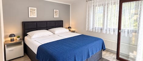 A bedroom with a bed, bedside tables, a ceiling fan, and a window with curtains.