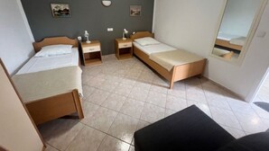 Une chambre avec deux lits simples, une petite table, une chaise et un miroir au mur.