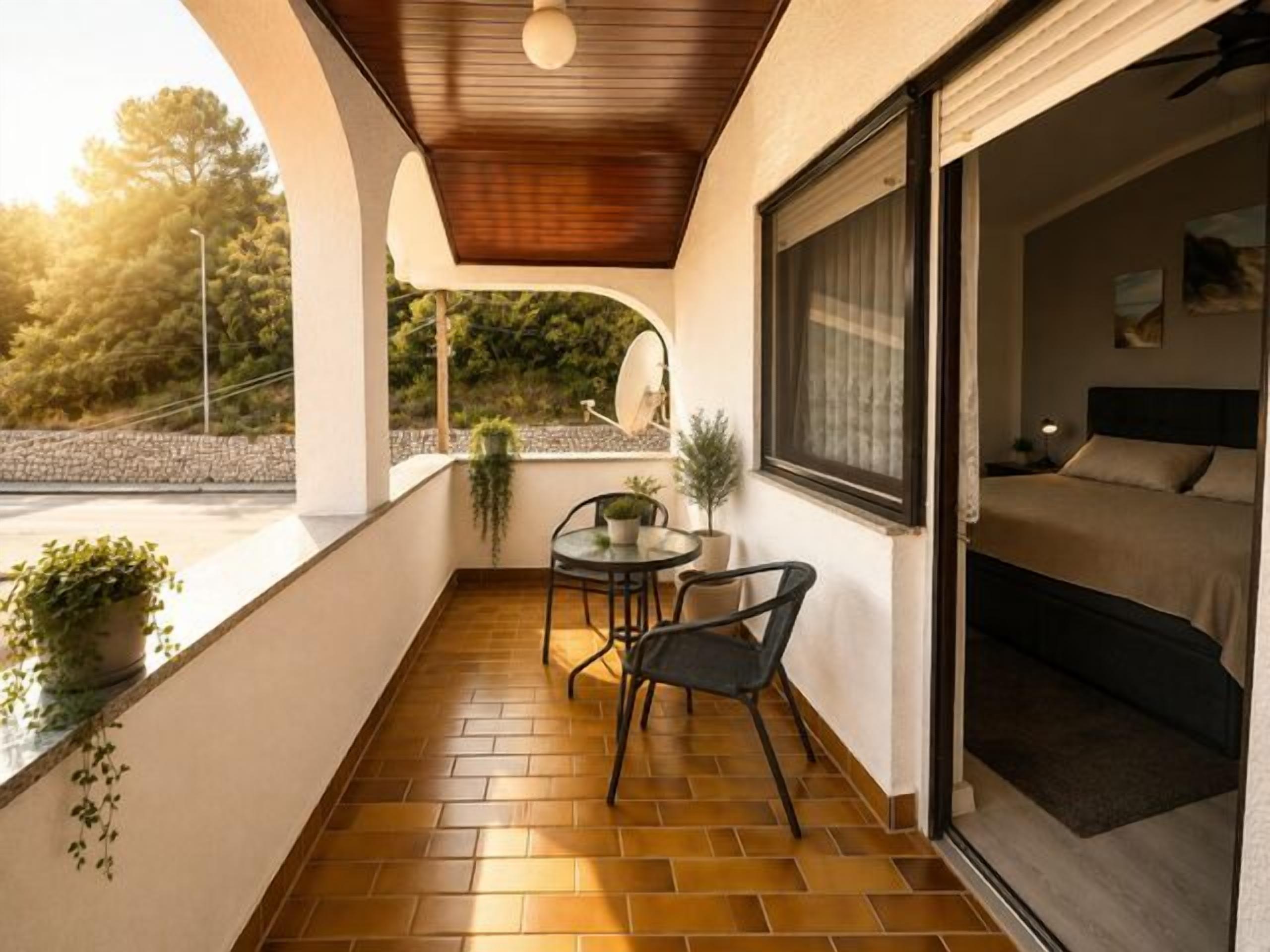 Ein Balkon mit Fliesenboden, einem Tisch mit Stühlen und einem Bett mit Fenster.