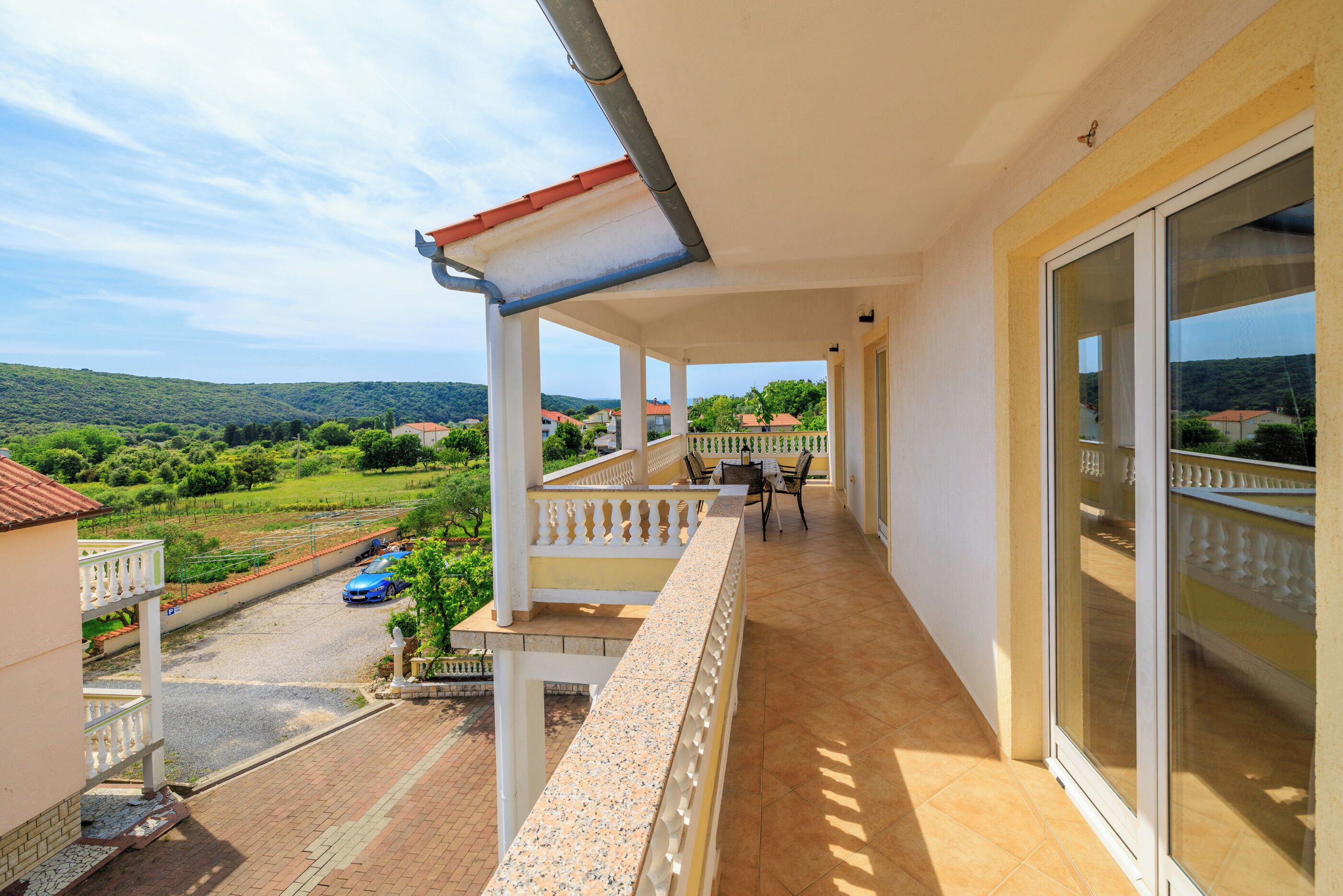 A balcony with a view of a green landscape and a road.