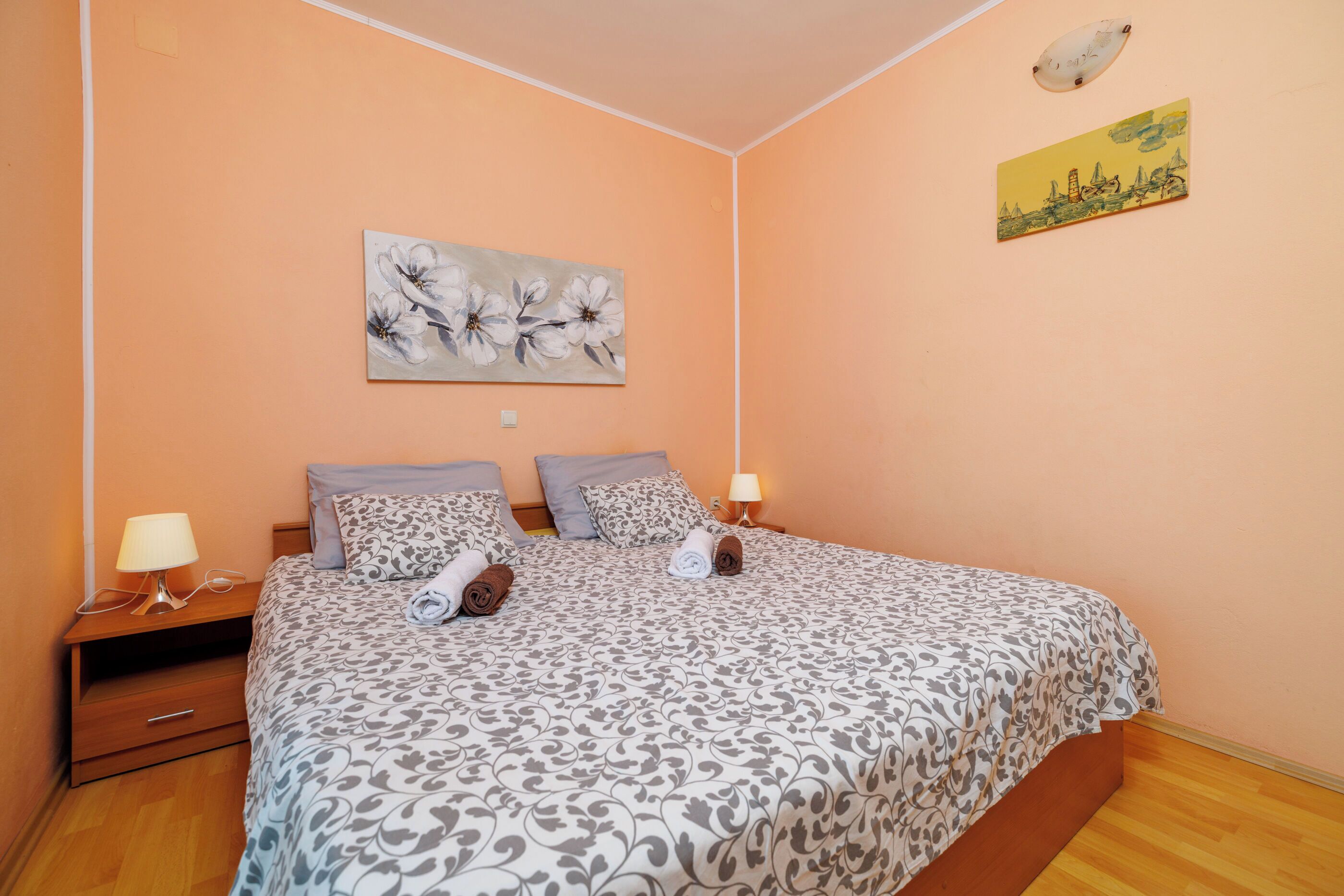 Ein Schlafzimmer mit einem Bett, zwei Kissen, einem Nachttisch mit Lampe und einem Bild an der Wand.