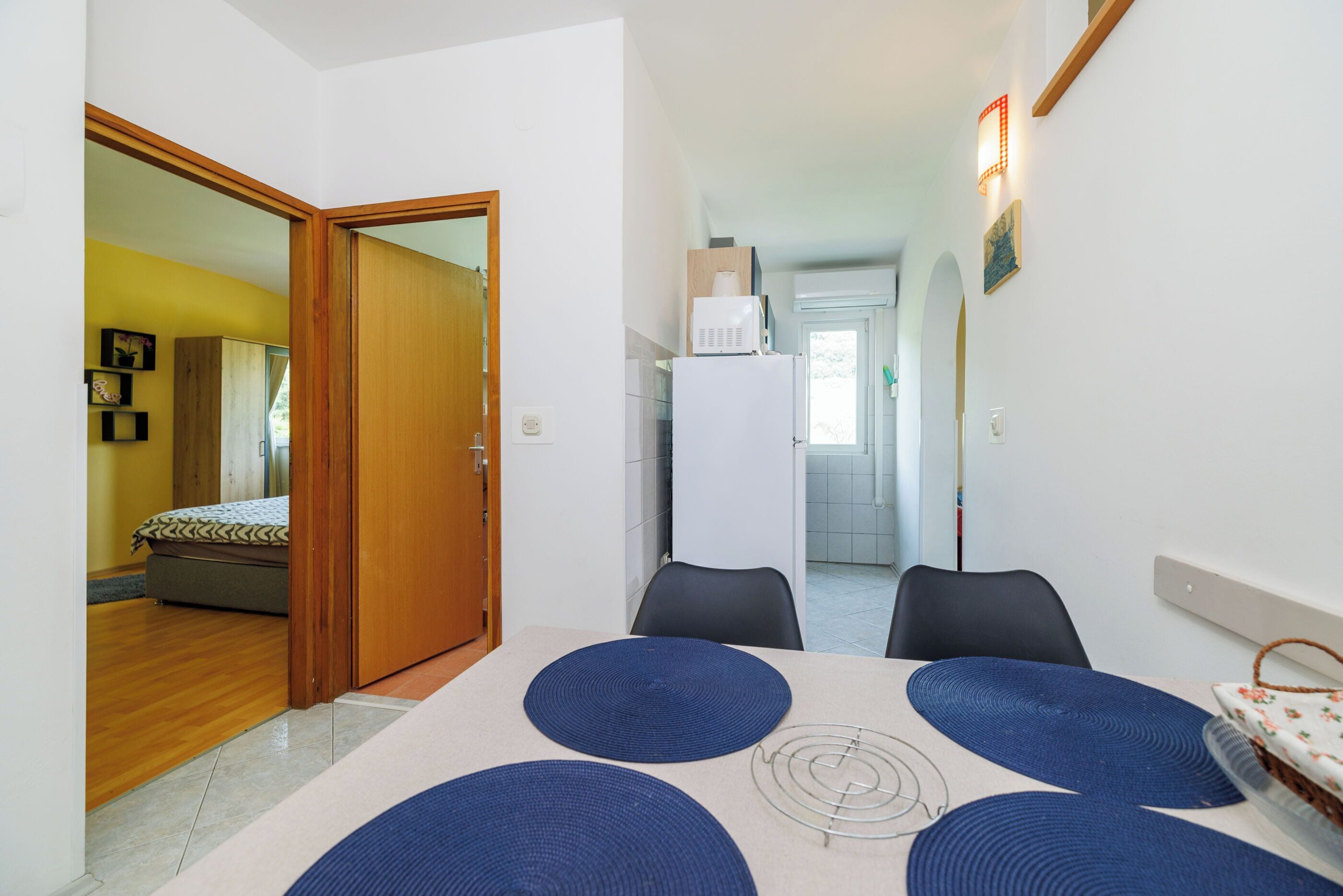 A compact living space with a dining area, a kitchen, and a bedroom.
