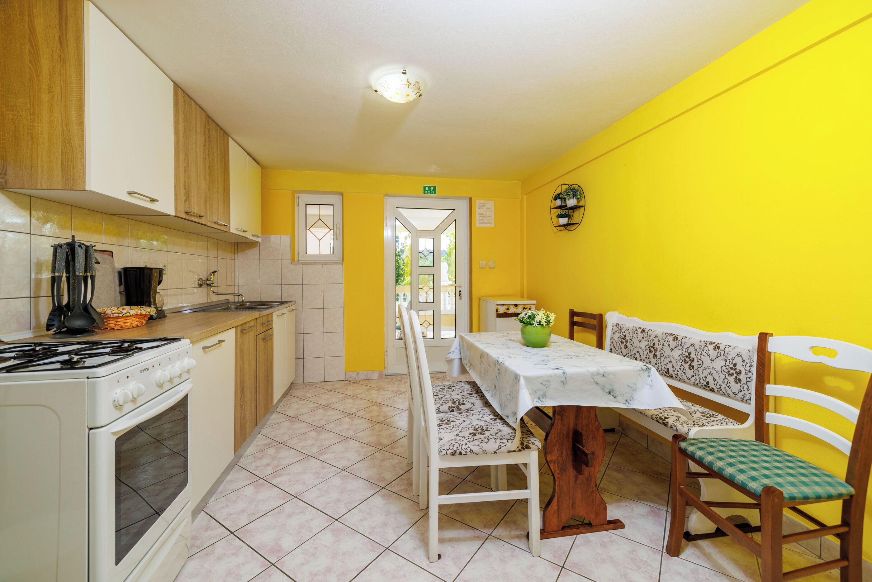 A kitchen with a stove, sink, and dining area with a table and chairs.