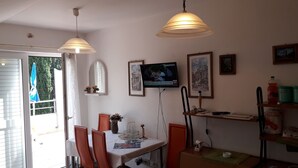 Een eethoek met een tafel, stoelen en een aan de muur bevestigde televisie.