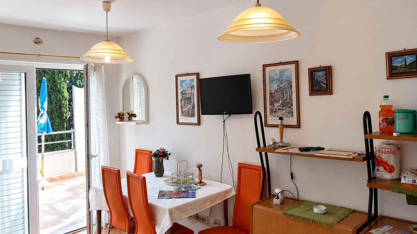 A dining area with a table, chairs, a television, and framed pictures on the wall.