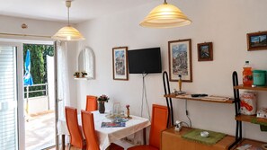 A dining area with a table, chairs, a television, and framed pictures on the wall. - Apartments Marija (Dubrovnik)