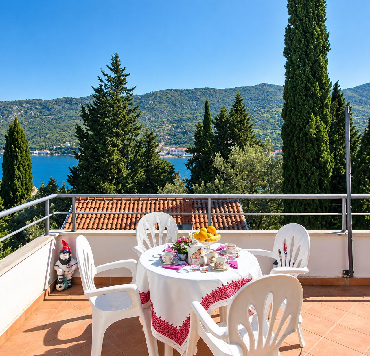 Una terraza con mesa dispuesta para cuatro, con vistas panorámicas a un lago y montañas.