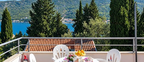 A terrace with a table set for four, overlooking a scenic view of a lake and mountains.