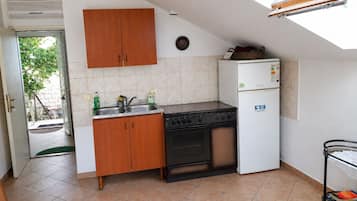 A compact kitchen with a stove, sink, and a small refrigerator.