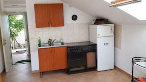A compact kitchen with a stove, sink, and a small refrigerator. - Apartments Marija (Dubrovnik)