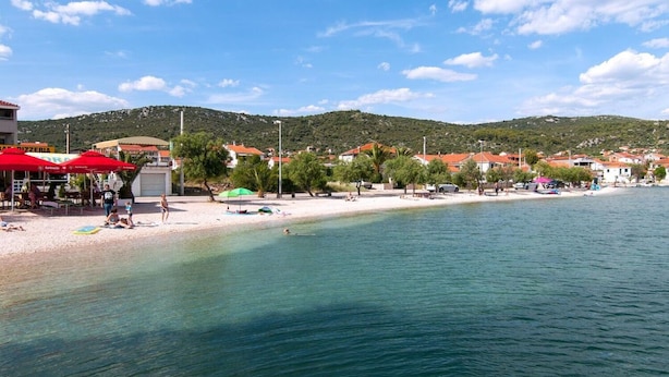 A coastal beach with umbrellas, beach chairs, and a clear view of the sea. - Apartments Mari (Marina)