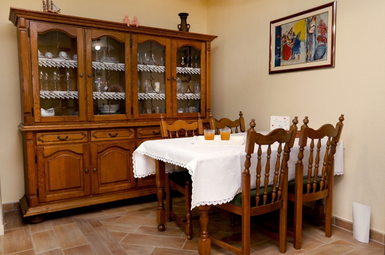 Zona pranzo con un mobile in legno, un tavolo con tovaglia bianca e sedie.