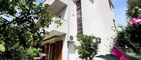 Un edificio moderno con un diseño arquitectónico único, que cuenta con un balcón y un pequeño jardín con plantas y flores.