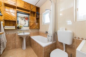 A bathroom with a sink, bathtub, toilet, and shower. - Apartment Stipe (Makarska)