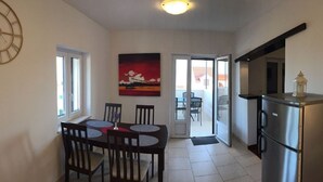 A compact kitchen with a dining area, a refrigerator, and a painting on the wall. - Apartment Nikola M (Bol)