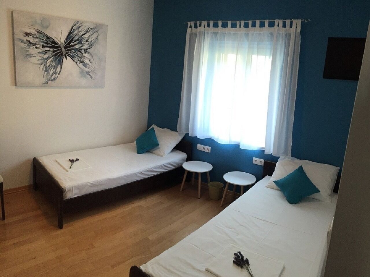 A room with two single beds, a small table, and a chair.