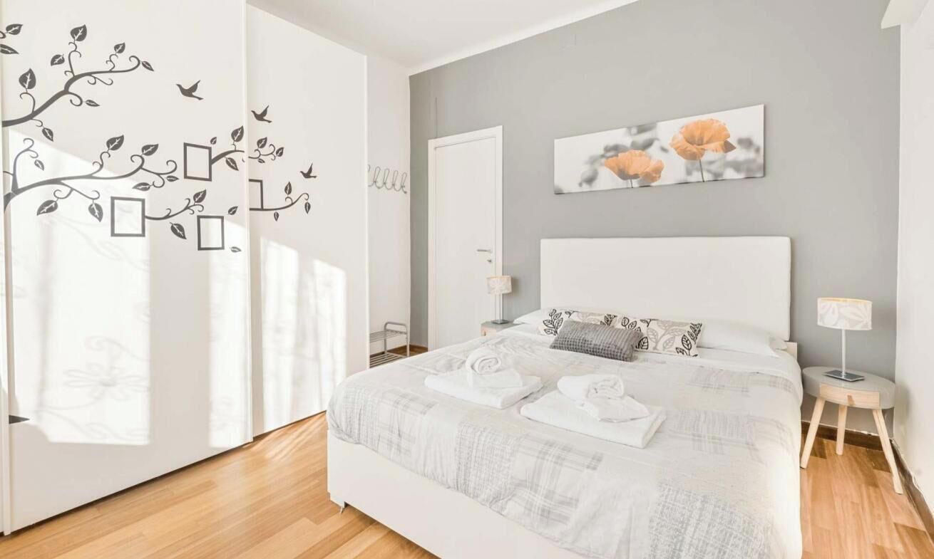 A bedroom with a large bed, a bedside table, a lamp, and a painting on the wall.