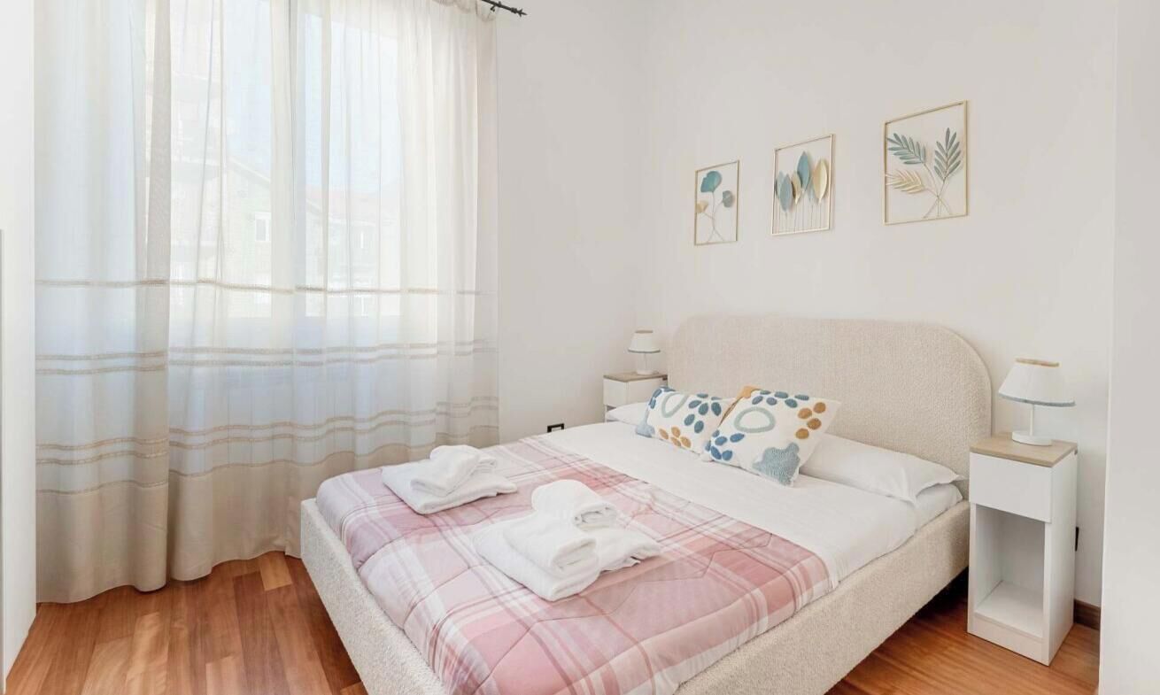 A bedroom with a bed, bedside tables, and curtains.