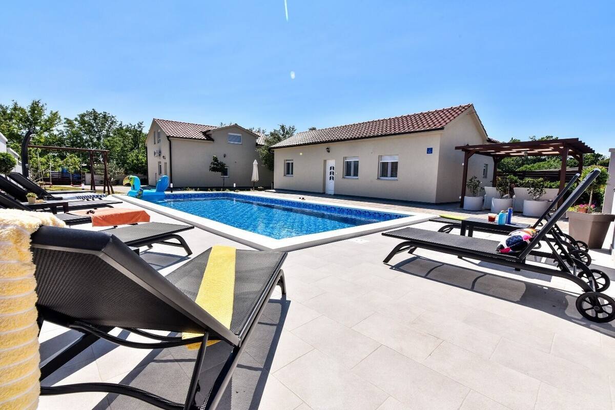 A swimming pool with lounge chairs and a pergola.