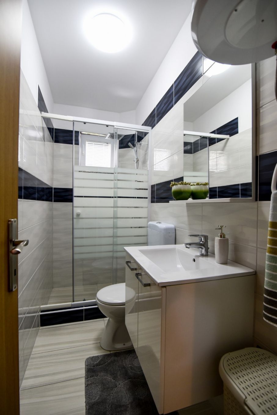 A modern bathroom with a glass shower enclosure, a white sink, and a toilet.