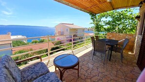 A balcony with a table and chairs, overlooking a scenic view of the sea and buildings. - Apartment Jakov (Okrug)