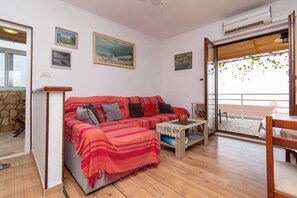 A cozy living room with a sofa, a coffee table, and a view of the outside. - Apartment Jakov (Okrug)